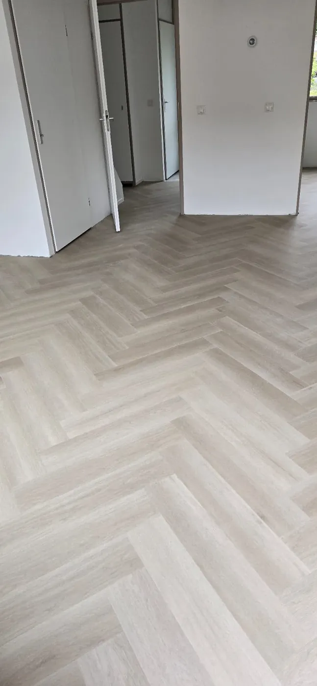 Lichte visgraatvloer bij een open deur