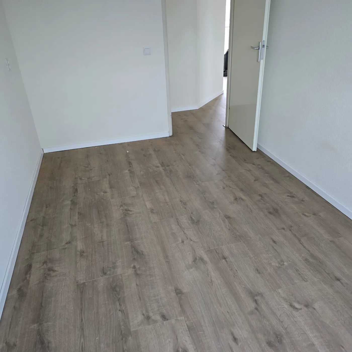 Lichte ruimte met een bruingrijze houtlook vloer